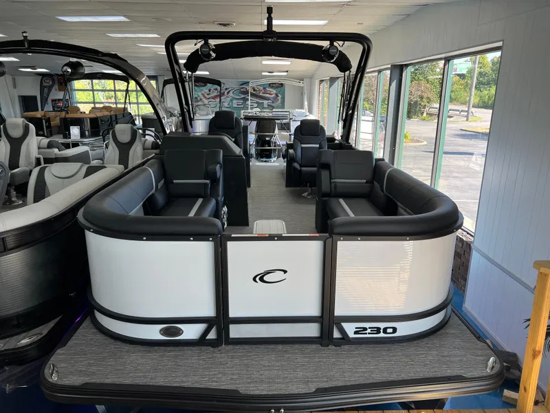 Slide: The Image of 2025 Crest Caribbean LX 230 SLRC pontoon boat in showroom, featuring sleek black and white design. - 3