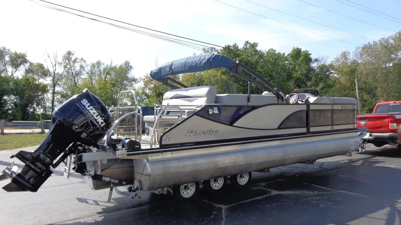 Slide: The Image of 2022 Manitou 23 SES Bench pontoon boat with Suzuki outboard motor on trailer. - 2