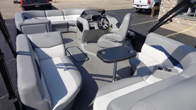 Slide: The Image of 2022 Manitou 23 SES Bench pontoon boat interior with gray seating and steering console. - 8
