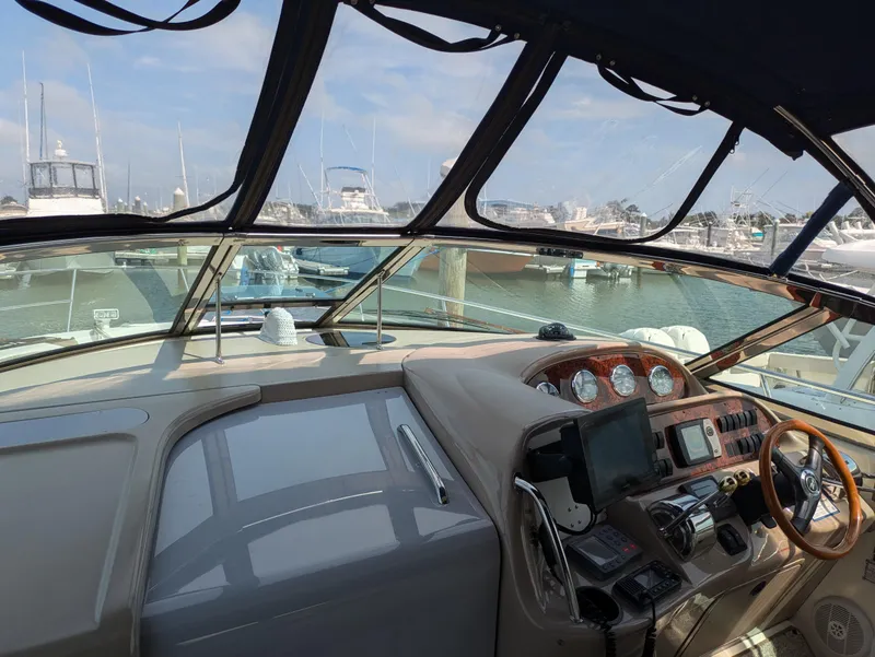 Slide: The Image of 2004 Sea Ray 360 Sundancer helm with marina view, featuring navigation instruments and steering wheel. - 6