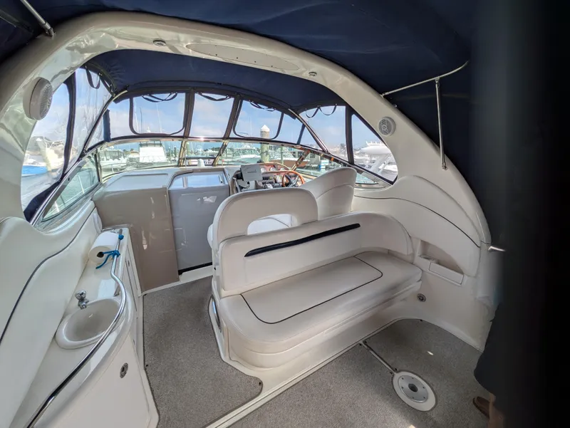 Slide: The Image of 2004 Sea Ray 360 Sundancer interior with seating, helm, and sink, featuring a blue canopy. - 7