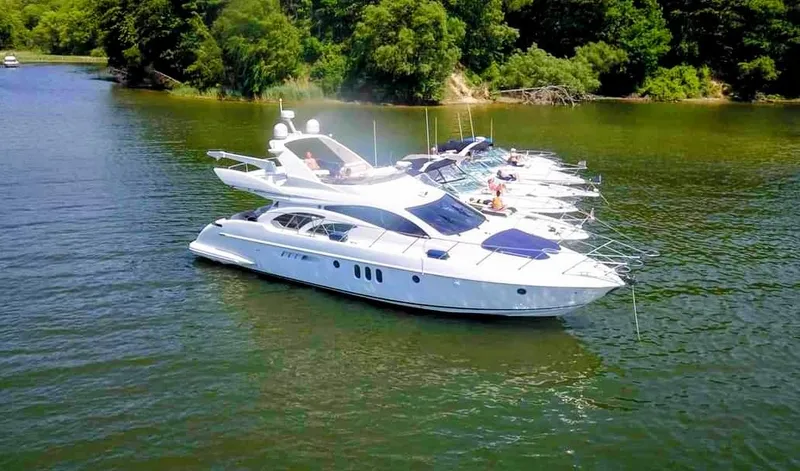 Slide: The Image of Azimut 55 yacht, 2002 model, anchored on a serene lake with lush greenery. - 1