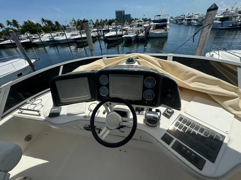 Slide: The Image of 2008 Sea Ray 44 Sedan Bridge helm with marina view, featuring dual displays and controls. - 20