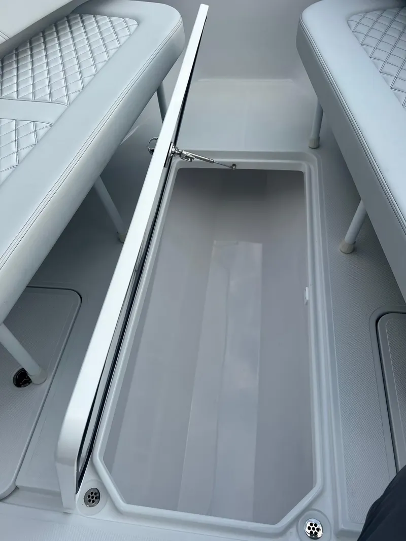 Slide: The Image of 2025 Bluewater 25 T boat interior with open storage compartment and cushioned seating. - 11