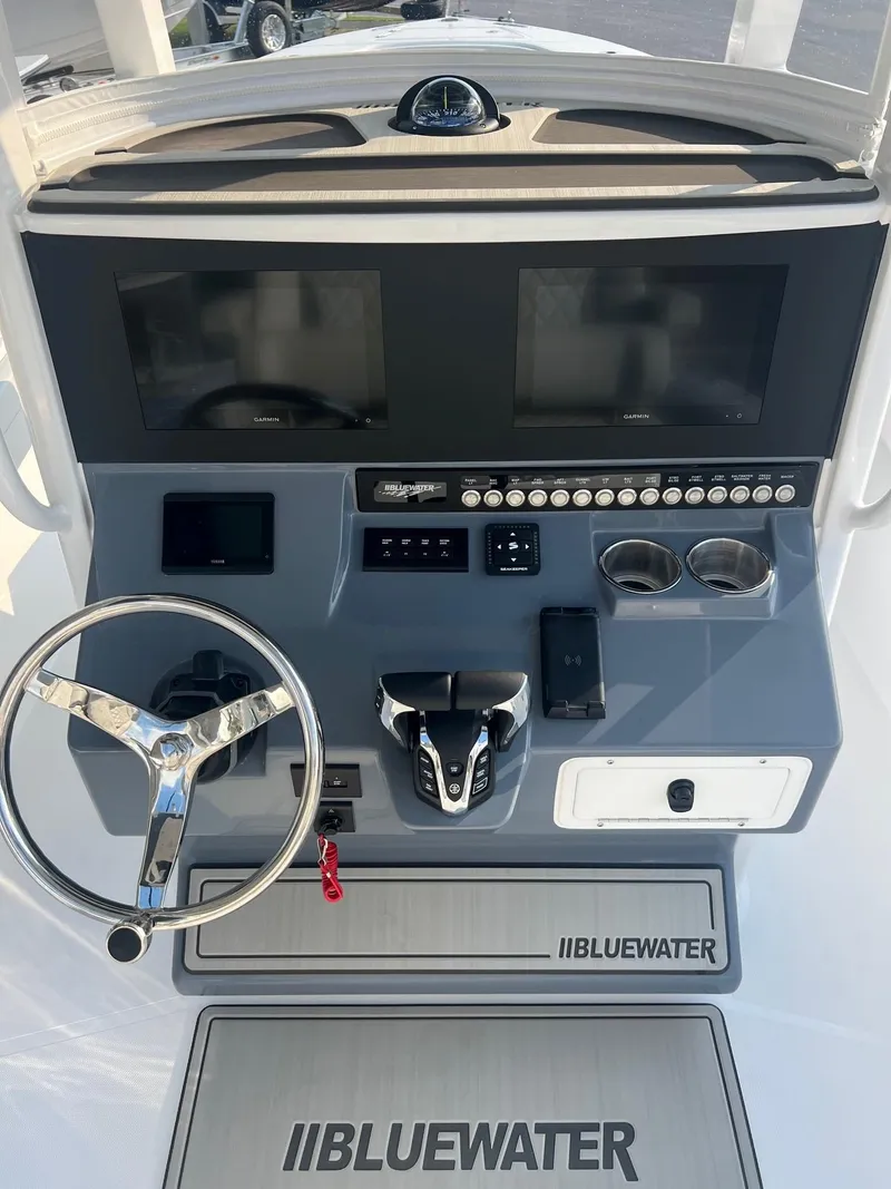Slide: The Image of 2025 Bluewater 25 T boat dashboard with dual screens and steering wheel. - 12