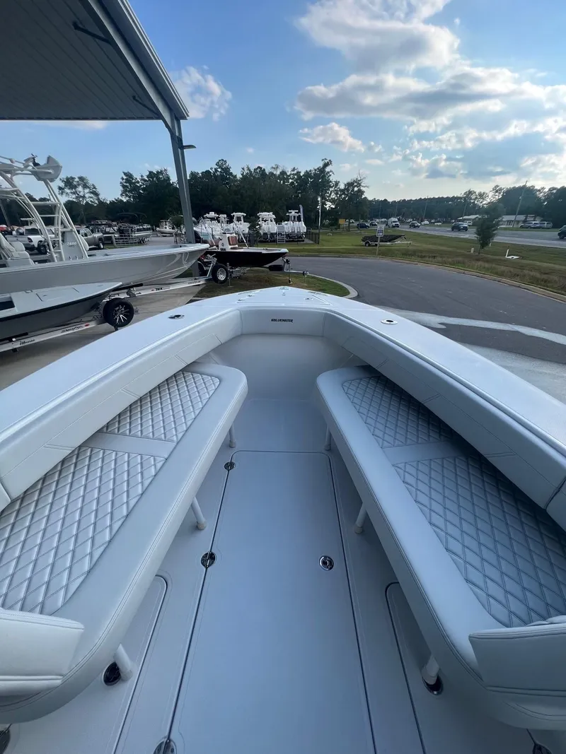 Slide: The Image of 2025 Bluewater 25 T boat with cushioned seating, docked under a clear sky. - 5