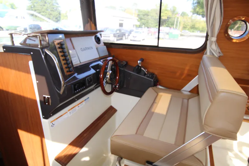 Slide: The Image of 2023 Ranger Tugs R-27 Luxury Edition helm with Garmin navigation and beige seating. - 12