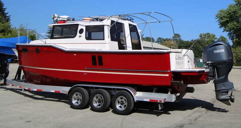 Slide: The Image of 2023 Ranger Tugs R-27 Luxury Edition boat on trailer, red exterior, Yamaha outboard motor. - 3