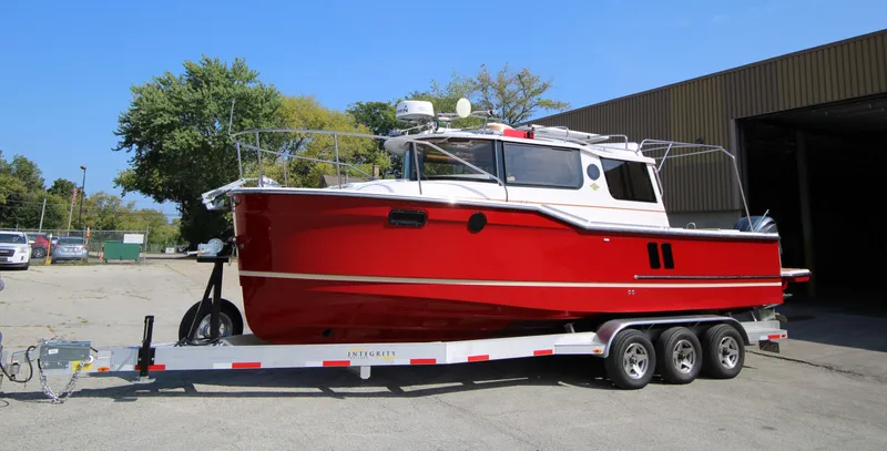 Slide: The Image of 2023 Ranger Tugs R-27 Luxury Edition boat on trailer, vibrant red hull, parked outdoors. - 30