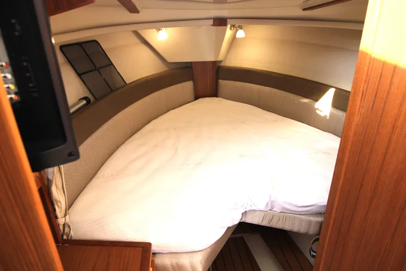 Slide: The Image of 2023 Ranger Tugs R-27 Luxury Edition cabin interior with cozy bed and warm lighting. - 7