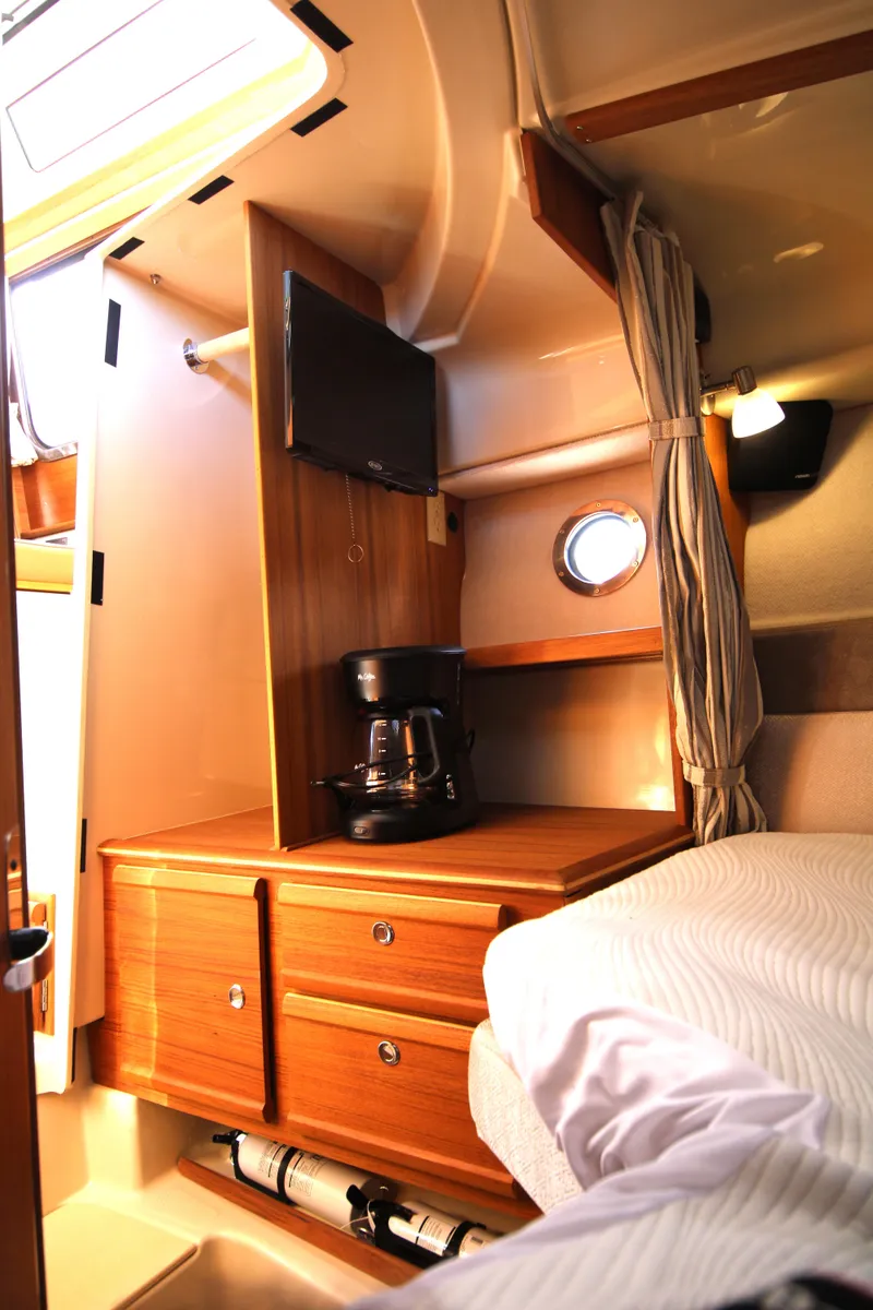 Slide: The Image of 2023 Ranger Tugs R-27 Luxury Edition cabin interior with TV and coffee maker. - 8