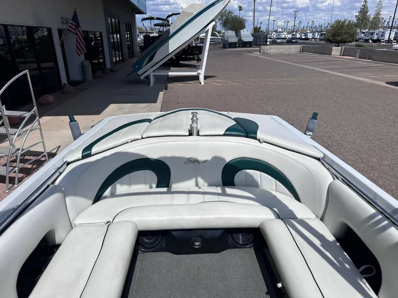 Slide: The Image of 2003 Sanger Z210 boat interior with white and green seating, parked outdoors. - 4