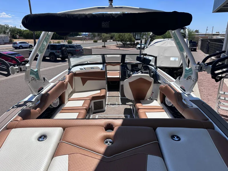 Slide: The Image of 2022 Supreme S220 boat interior with brown and white seating, parked outdoors. - 10