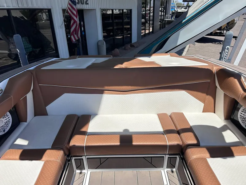 Slide: The Image of 2022 Supreme S220 boat interior with brown and white seating, docked near a building. - 9