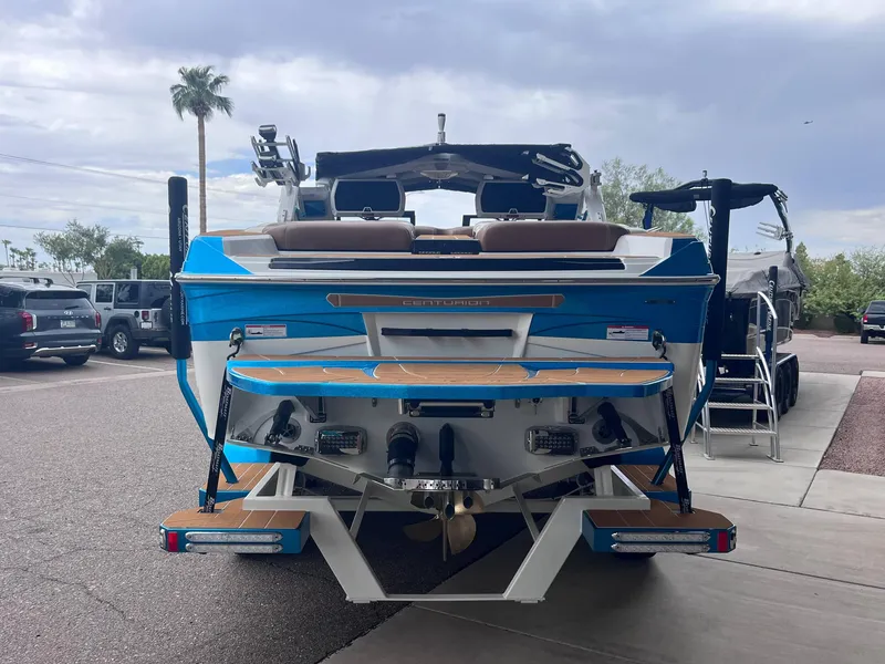 Slide: The Image of 2025 Centurion Ri245 boat, blue and white, parked on a sunny day. - 4