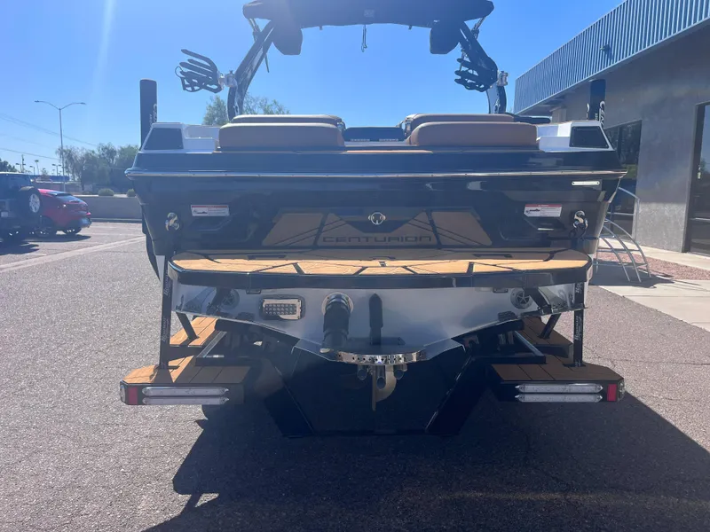 Slide: The Image of 2025 Centurion Fe23 boat rear view in a parking lot under clear blue sky. - 3