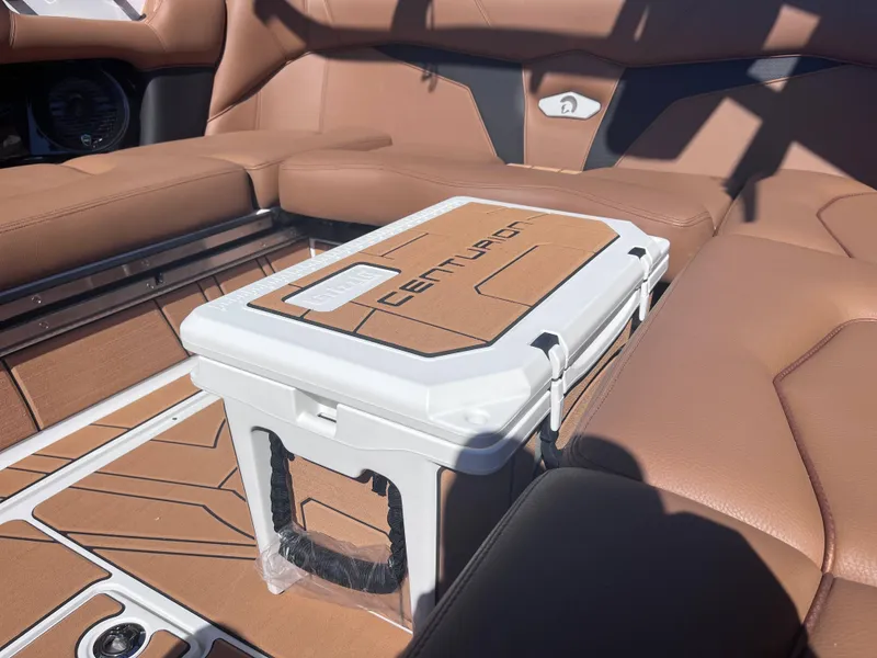 Slide: The Image of 2025 Centurion Fe23 boat interior with tan seating and branded cooler. - 8