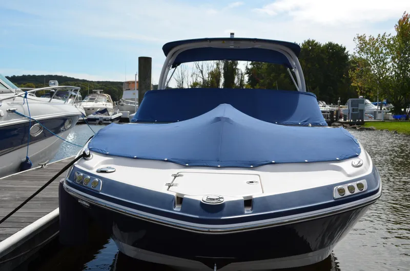 Slide: The Image of 2016 Chaparral 250 Suncoast boat docked with blue cover, surrounded by water and other boats. - 6