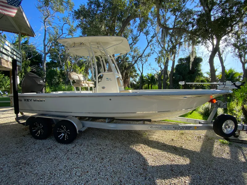 Slide: The Image of 2017 Key West 230 Bay Reef boat on trailer, parked outdoors under trees. - 1