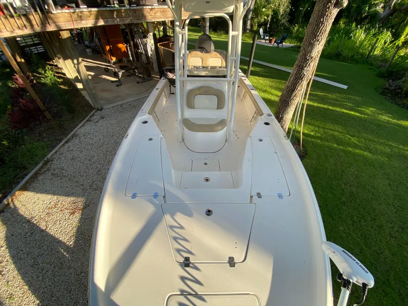 Slide: The Image of 2017 Key West 230 Bay Reef boat, top view, parked on gravel near lush greenery. - 16