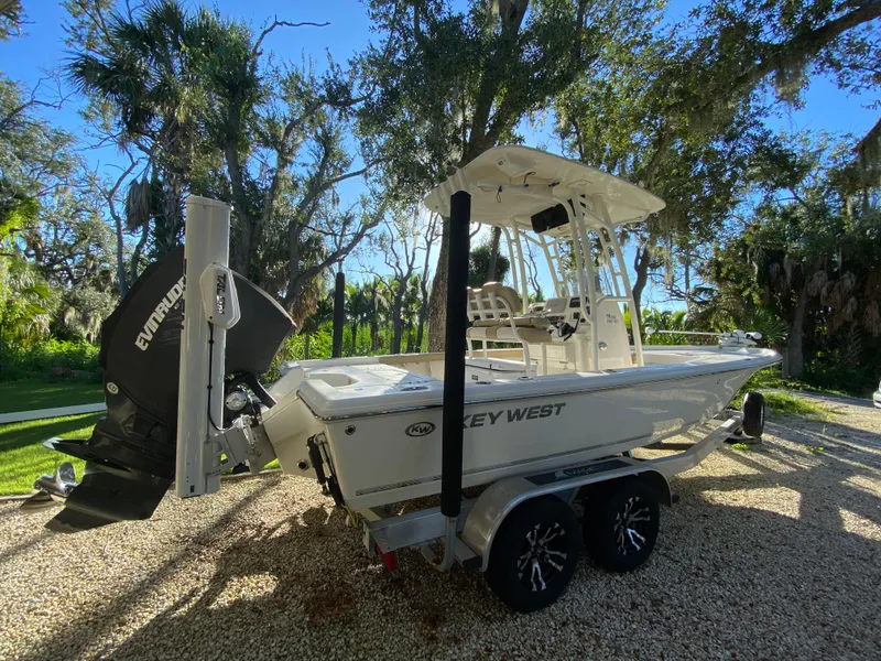 Slide: The Image of 2017 Key West 230 Bay Reef boat on trailer, parked outdoors under trees. - 2