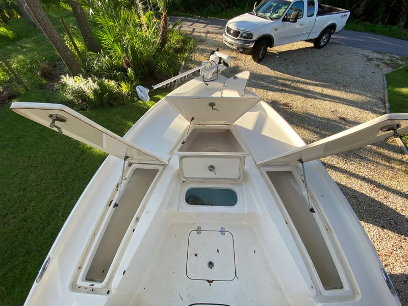 Slide: The Image of 2017 Key West 230 Bay Reef boat with open storage compartments, parked near a white truck. - 22