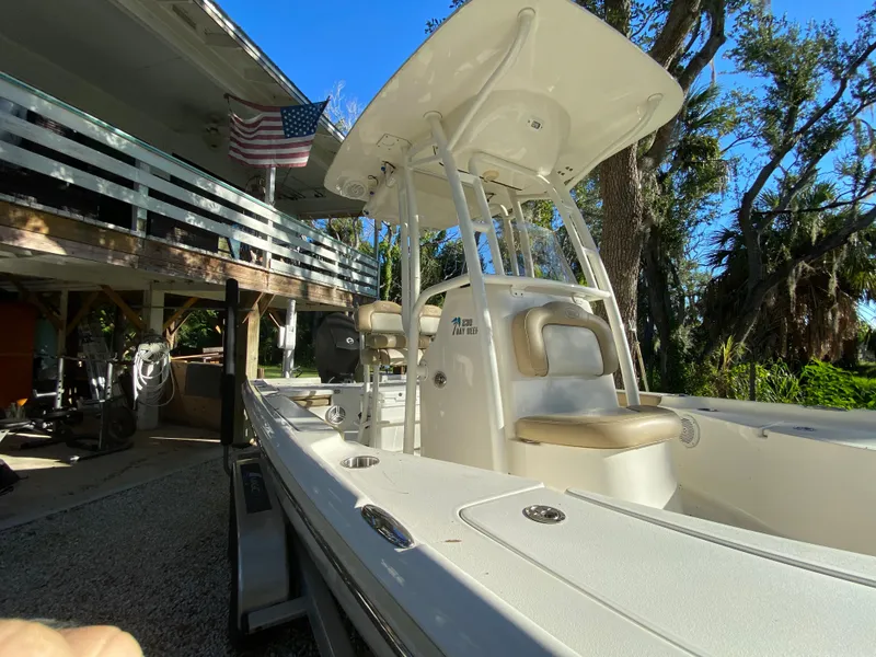 Slide: The Image of 2017 Key West 230 Bay Reef boat parked under a deck with American flag. - 9