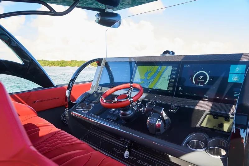 Slide: The Image of 2021 Midnight Express 43' Solstice boat dashboard with red steering wheel and navigation screens. - 16