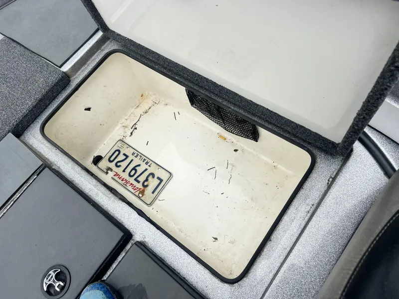 Slide: The Image of Open storage compartment in 2009 Ranger 208 VX boat with a trailer license plate inside. - 12