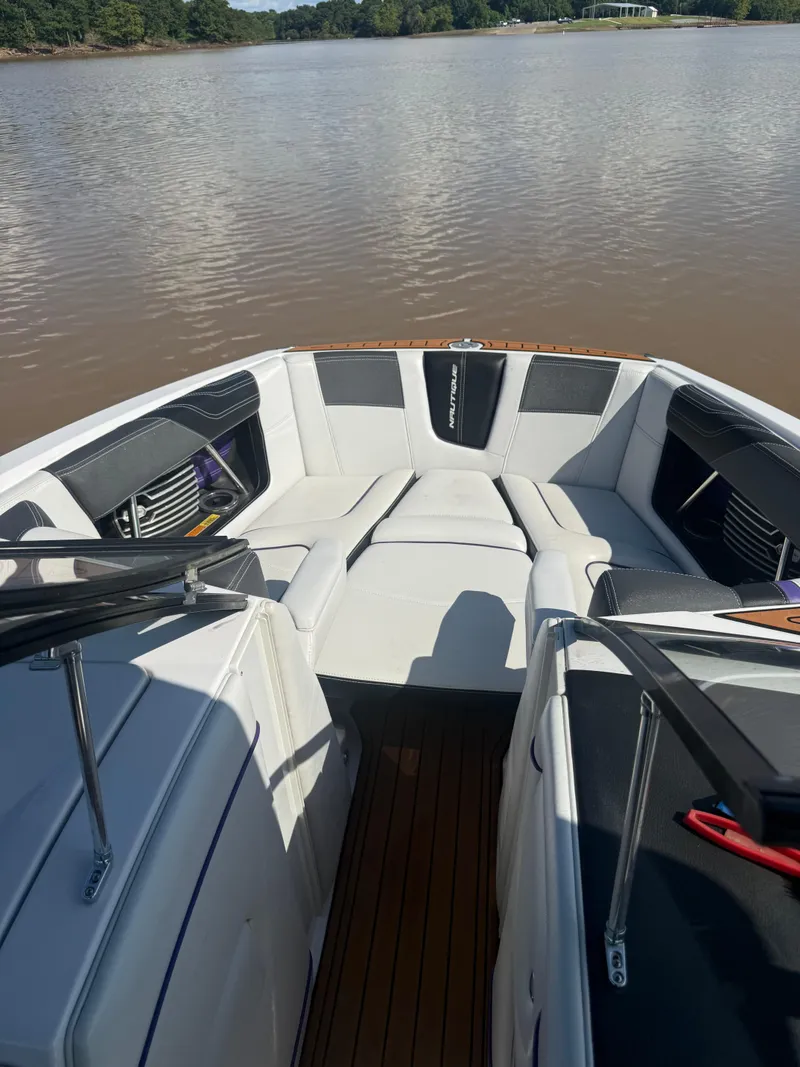 Slide: The Image of 2014 Nautique Super Air Nautique G21 boat interior with white seating on a calm lake. - 10