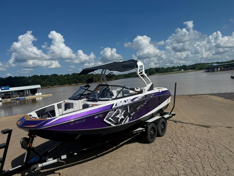 Slide: The Image of 2014 Nautique Super Air Nautique G21 boat on trailer by a lake under blue sky. - 15
