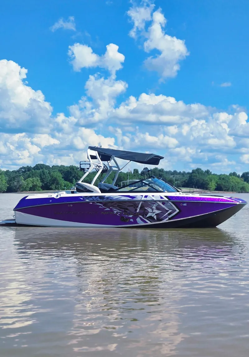 Slide: The Image of 2014 Nautique Super Air Nautique G21 boat on a calm lake under a blue sky. - 17