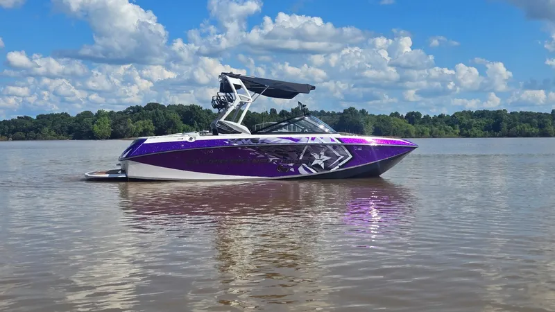 Slide: The Image of 2014 Nautique Super Air Nautique G21 boat on a calm lake under a blue sky. - 20