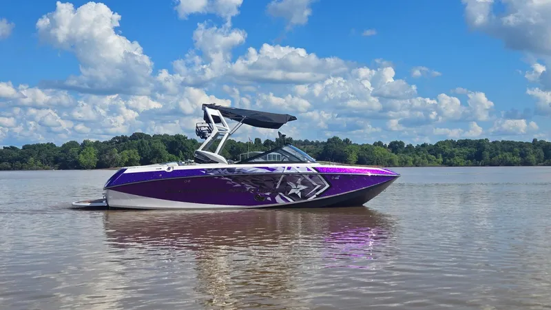 Slide: The Image of 2014 Nautique Super Air Nautique G21 boat on a calm lake under a blue sky. - 23