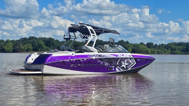 Slide: The Image of 2014 Nautique Super Air Nautique G21 boat on a lake, featuring a vibrant purple design. - 4