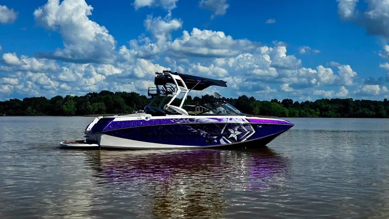 Slide: The Image of 2014 Nautique Super Air Nautique G21 boat on a calm lake under a cloudy sky. - 7