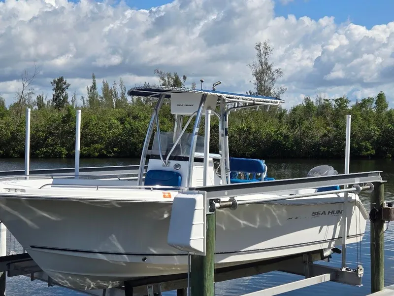 Slide: The Image of 2008 Sea Hunt Triton 220 boat docked on a lift by a scenic waterway. - 0