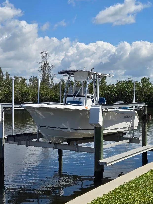 Slide: The Image of 2008 Sea Hunt Triton 220 boat on lift, under blue sky with clouds. - 1