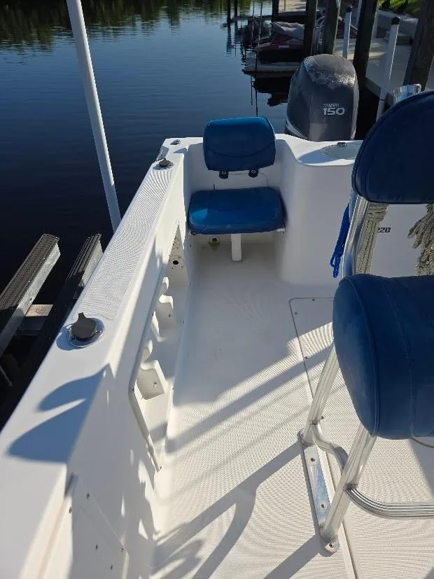 Slide: The Image of 2008 Sea Hunt Triton 220 boat interior with blue seating, docked by calm water. - 16