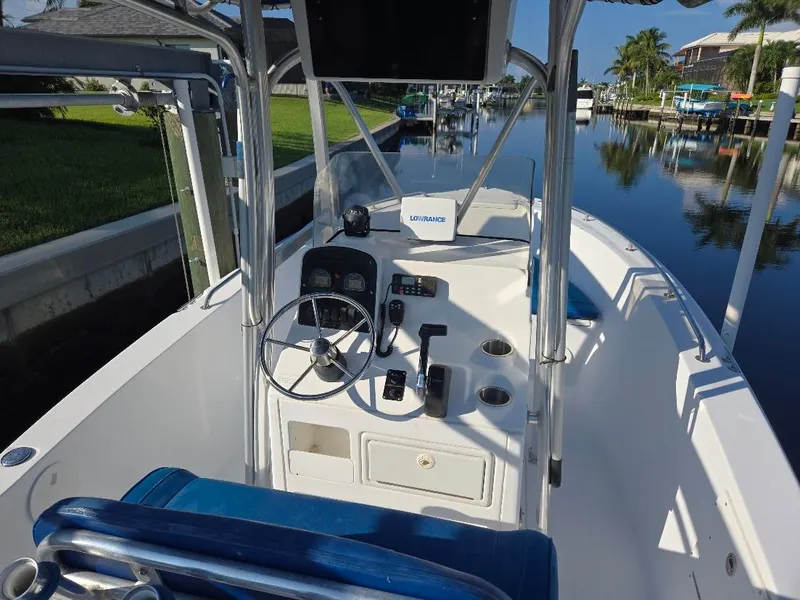 Slide: The Image of 2008 Sea Hunt Triton 220 boat interior with steering wheel and controls, docked by a canal. - 2
