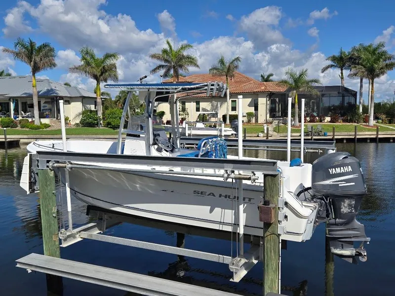 Slide: The Image of 2008 Sea Hunt Triton 220 boat on lift, with Yamaha motor, near waterfront homes and palm trees. - 20