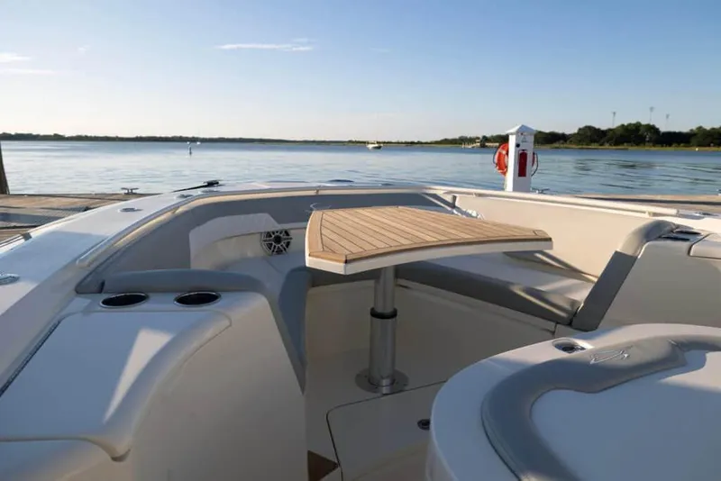 Slide: The Image of 2025 Scout 357 LXF boat interior with seating and table, overlooking calm waters. - 19