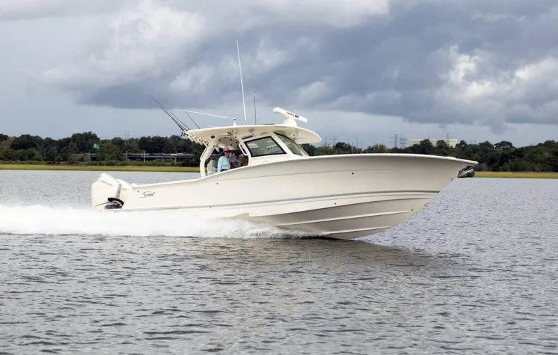 Slide: The Image of 2025 Scout 357 LXF boat cruising on a calm lake under cloudy skies. - 2