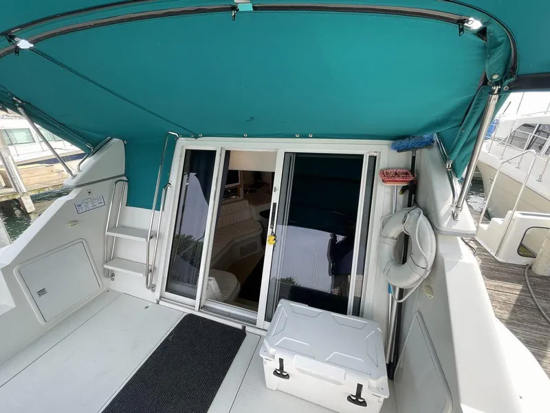 Slide: The Image of 1995 Carver 380 Santego yacht deck with teal canopy and sliding glass doors. - 11
