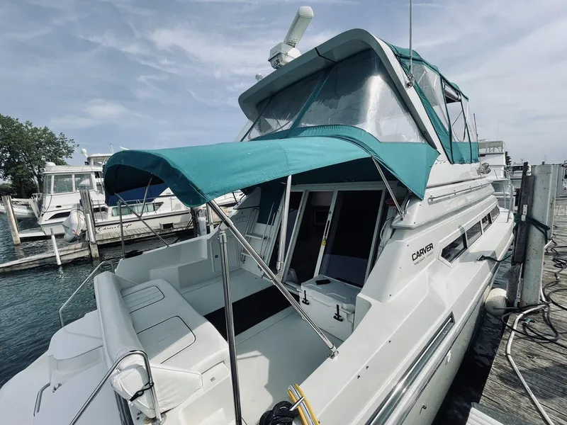 Slide: The Image of 1995 Carver 380 Santego yacht docked, featuring teal canopy and spacious deck. - 3