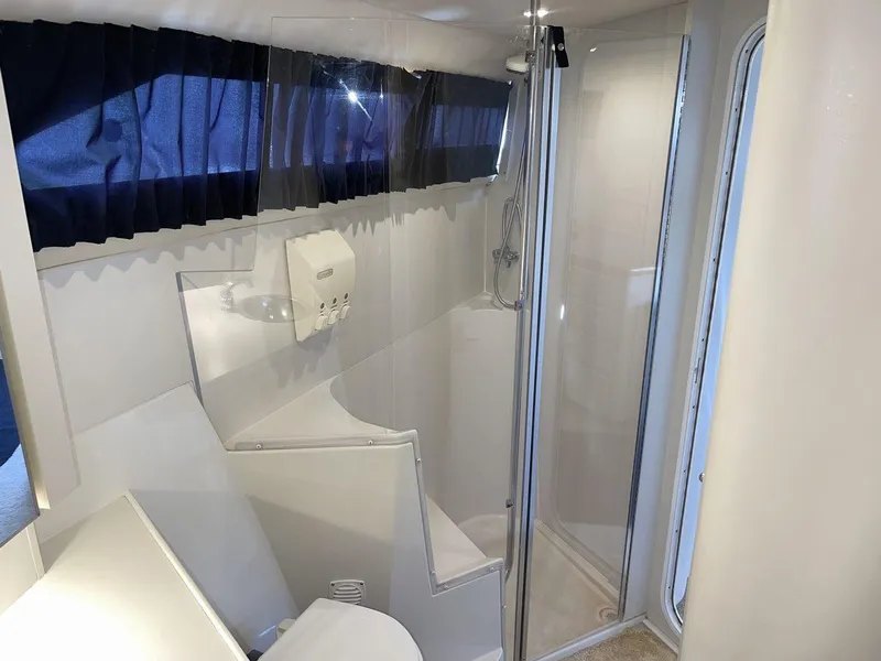 Slide: The Image of 1995 Carver 380 Santego bathroom with shower, white interior, and blue curtains. - 48