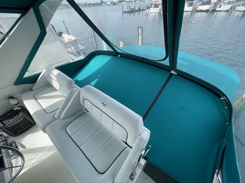 Slide: The Image of 1995 Carver 380 Santego boat interior with white seating and teal canopy, overlooking marina. - 14
