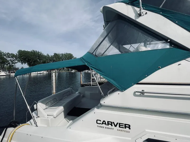 Slide: The Image of 1995 Carver 380 Santego yacht with teal canopy docked by the water. - 6