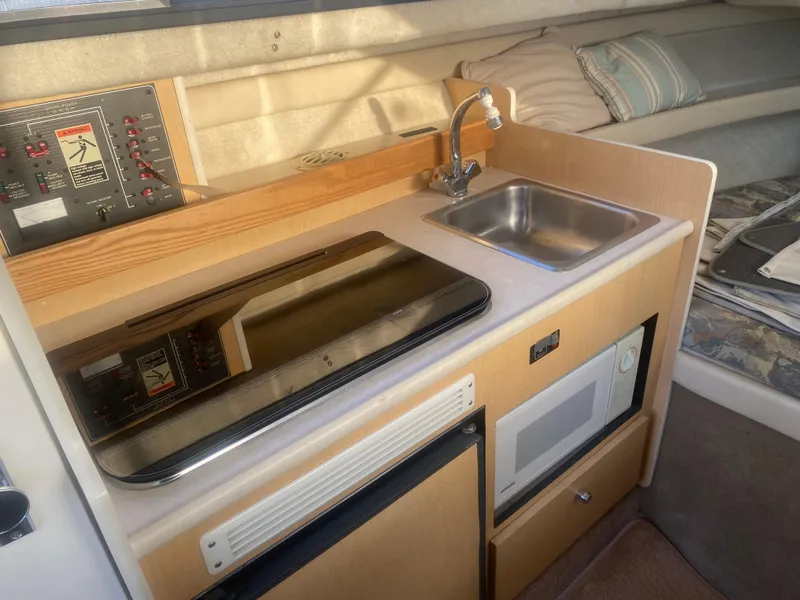 Slide: The Image of 2001 Bayliner 2452 Ciera Express kitchenette with stove, sink, microwave, and control panel. - 6