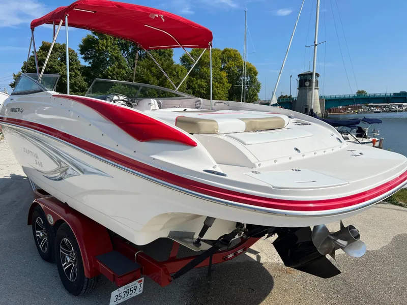 Slide: The Image of 2009 Rinker 246 Captiva Bowrider with red accents, docked near a marina. - 11
